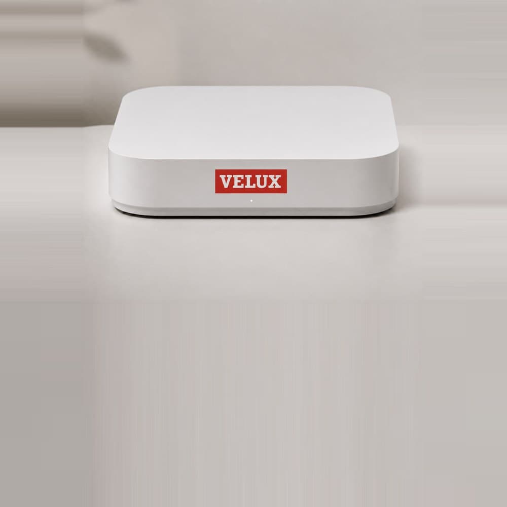 The Smart Climate hub, a small white unit with the VELUX logo on the front.